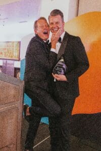 Interior designer Jeffrey Florentine receiving the 2024 IDS Award for Best Home Under 3,000 Sq. Ft. from celebrity presenter Carson Kressley, both smiling and celebrating on stage at the national gala in Santa Fe.